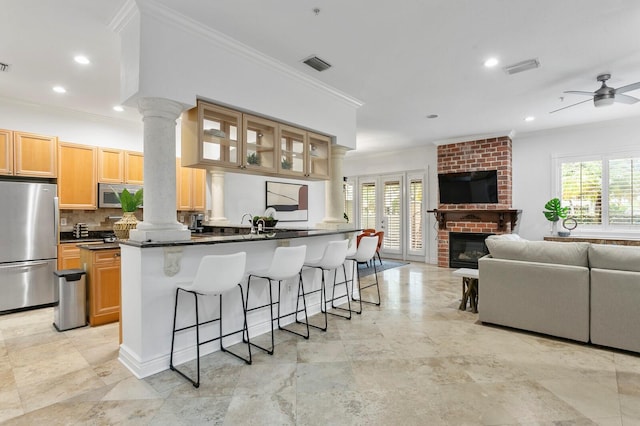 kitchen featuring stainless steel appliances, a breakfast bar, visible vents, open floor plan, and ornate columns