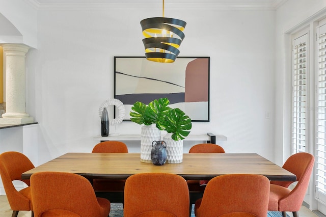 dining space featuring decorative columns and crown molding