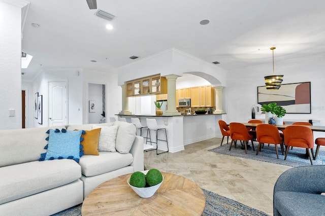 living room featuring decorative columns, visible vents, arched walkways, and crown molding