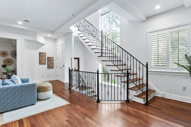 staircase with plenty of natural light, wood finished floors, and baseboards