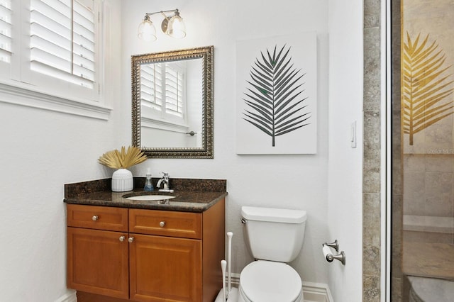 bathroom featuring a tile shower, vanity, toilet, and baseboards