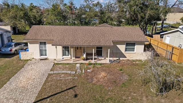 single story home featuring roof with shingles, fence, and stucco siding