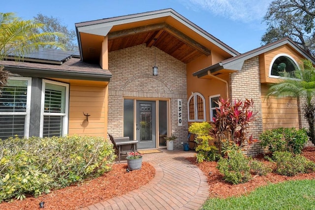 property entrance featuring solar panels and brick siding