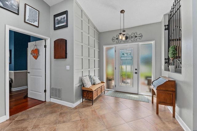 entrance foyer featuring baseboards, visible vents, a notable chandelier, and tile patterned floors