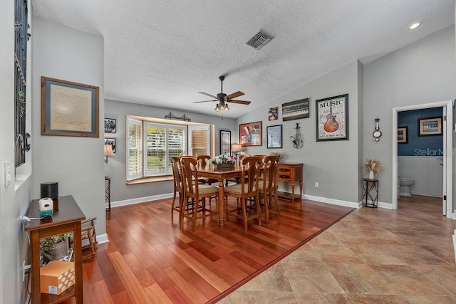 dining area with lofted ceiling, light wood-style flooring, visible vents, and a textured ceiling