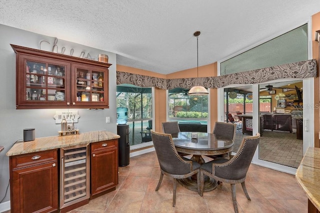 dining space featuring beverage cooler, a bar, a textured ceiling, and lofted ceiling