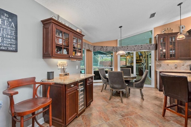 kitchen with lofted ceiling, visible vents, hanging light fixtures, and backsplash