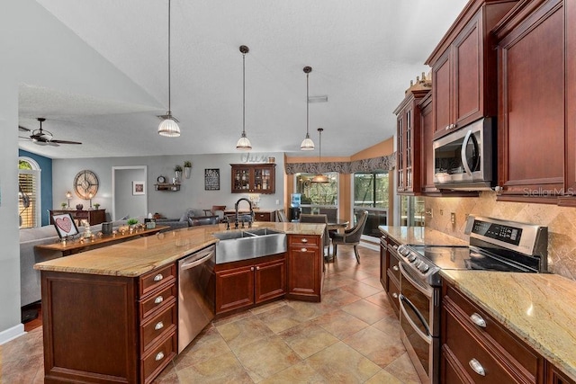 kitchen with appliances with stainless steel finishes, open floor plan, hanging light fixtures, vaulted ceiling, and a sink