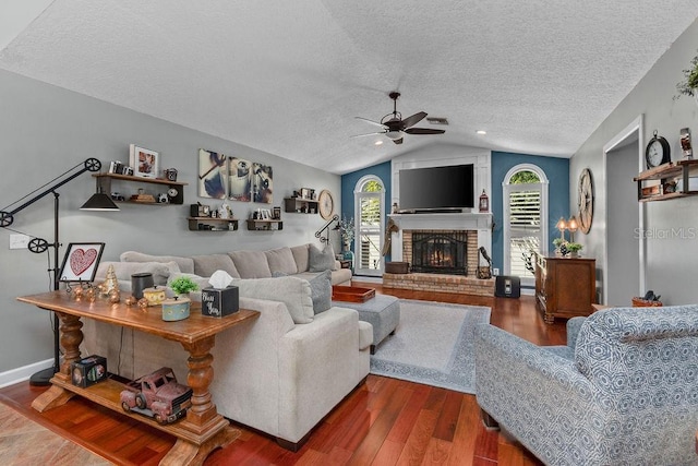 living room with plenty of natural light, a fireplace, vaulted ceiling, and wood finished floors