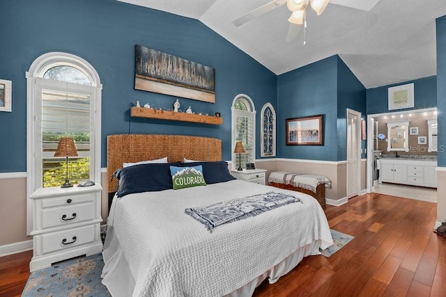 bedroom featuring connected bathroom, baseboards, vaulted ceiling, and wood finished floors