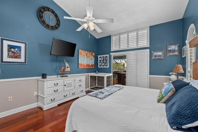 bedroom featuring lofted ceiling, a textured ceiling, baseboards, and wood finished floors