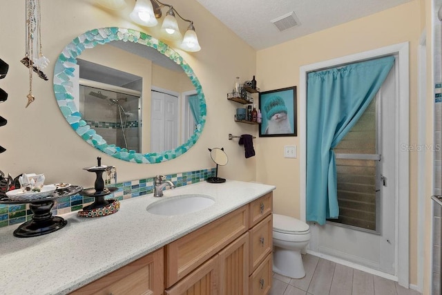 bathroom featuring visible vents, a shower stall, toilet, and vanity