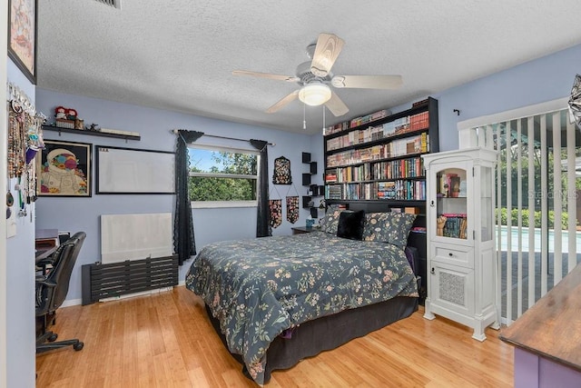 bedroom with a textured ceiling, a ceiling fan, and wood finished floors