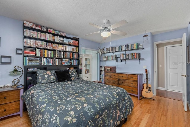 bedroom featuring a textured ceiling, wood finished floors, a ceiling fan, and baseboards