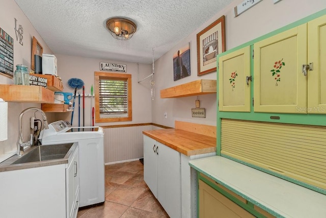 laundry area with light tile patterned floors, cabinet space, wainscoting, a textured ceiling, and separate washer and dryer