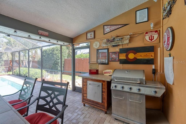 interior space featuring lofted ceiling, a sunroom, brick floor, and a textured ceiling