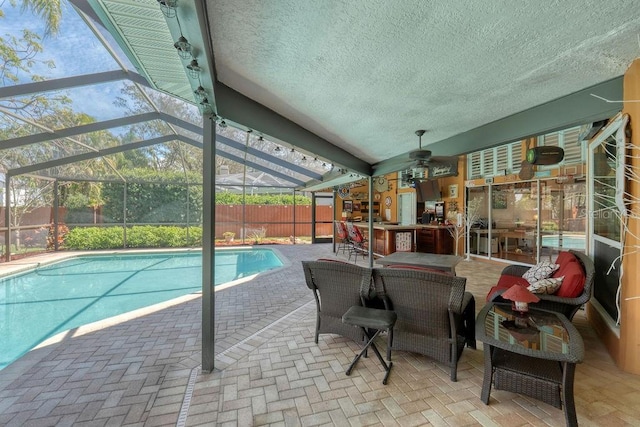 view of swimming pool featuring a fenced in pool, a ceiling fan, a patio, outdoor dry bar, and a lanai