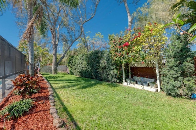 view of yard with glass enclosure and a fenced backyard