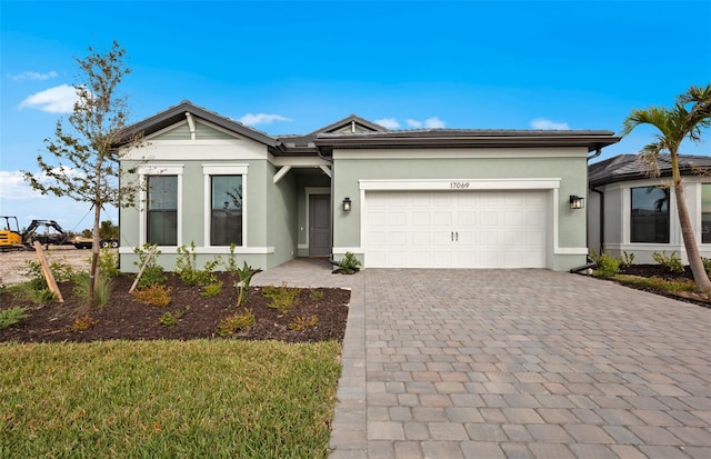 view of front of house featuring a garage, decorative driveway, and stucco siding