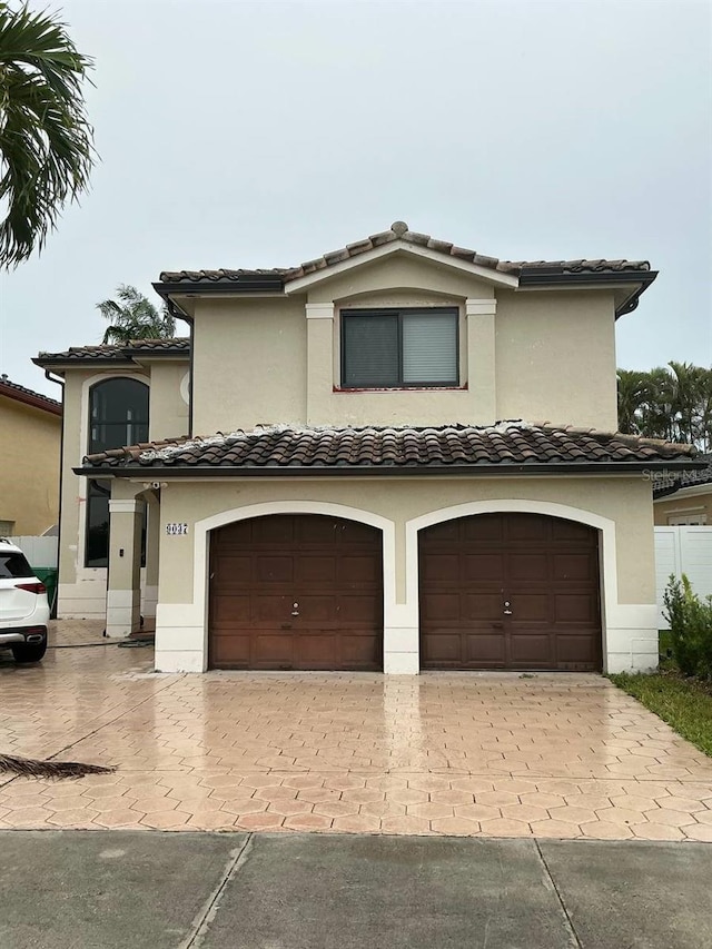 view of front of home featuring a garage, a tiled roof, decorative driveway, and stucco siding