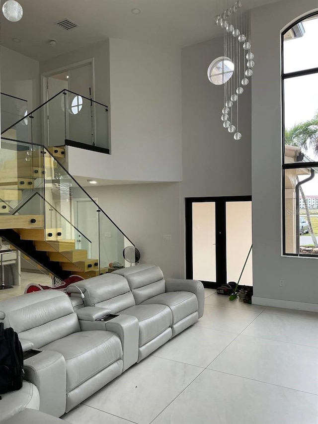 living area with a towering ceiling, visible vents, stairway, and tile patterned flooring