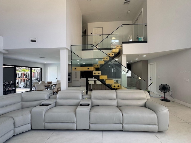 living room with baseboards, visible vents, a high ceiling, and stairs