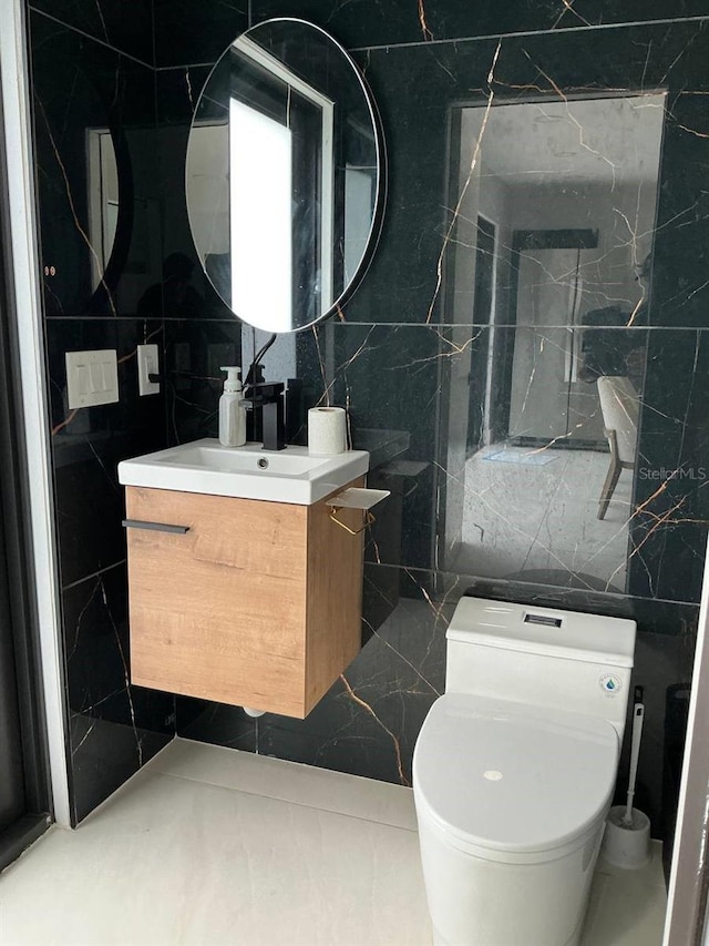 bathroom with toilet, tile walls, and vanity