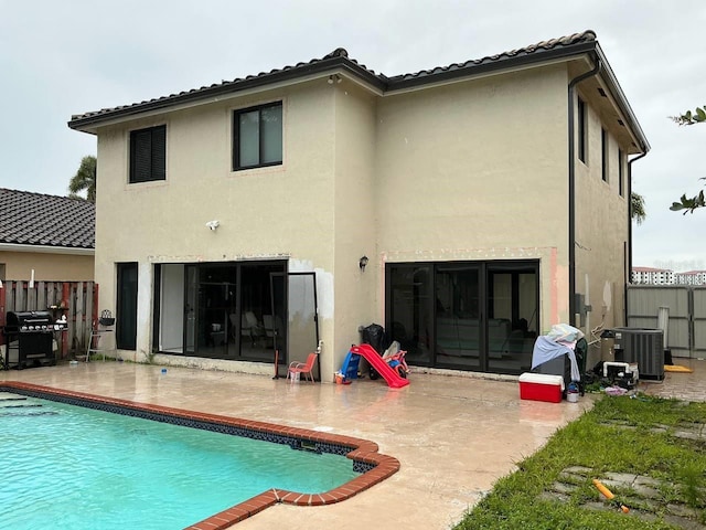 rear view of property with stucco siding, a patio area, fence, and central air condition unit