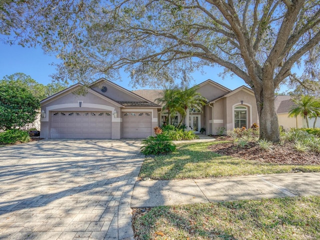 view of front of property with an attached garage, decorative driveway, and stucco siding