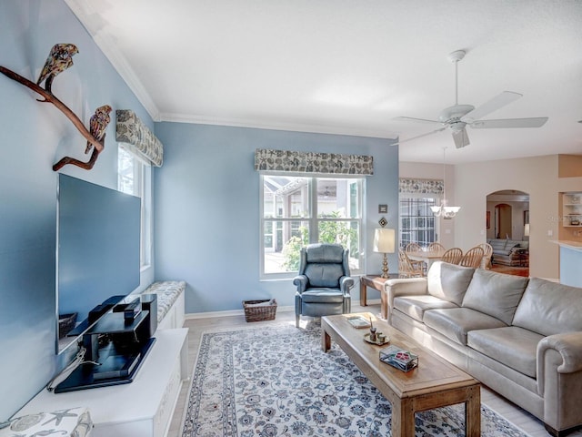 living room featuring ceiling fan with notable chandelier, plenty of natural light, arched walkways, and crown molding