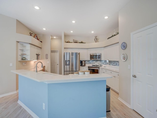 kitchen featuring stainless steel appliances, a peninsula, a sink, decorative backsplash, and open shelves