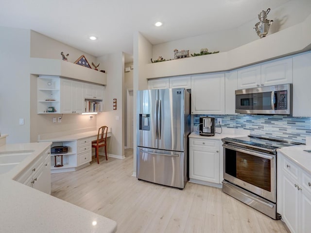 kitchen with built in desk, open shelves, light countertops, appliances with stainless steel finishes, and white cabinetry