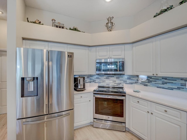 kitchen with white cabinets, appliances with stainless steel finishes, and decorative backsplash