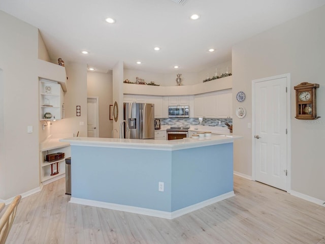 kitchen with stainless steel appliances, white cabinetry, light countertops, decorative backsplash, and light wood finished floors