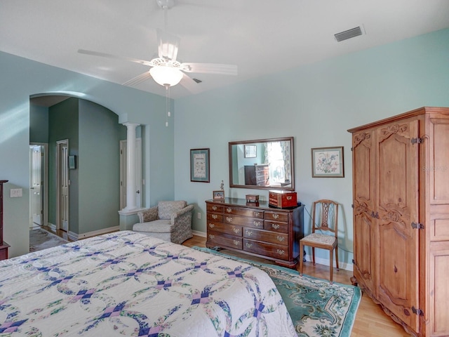 bedroom with arched walkways, ceiling fan, visible vents, baseboards, and light wood-style floors