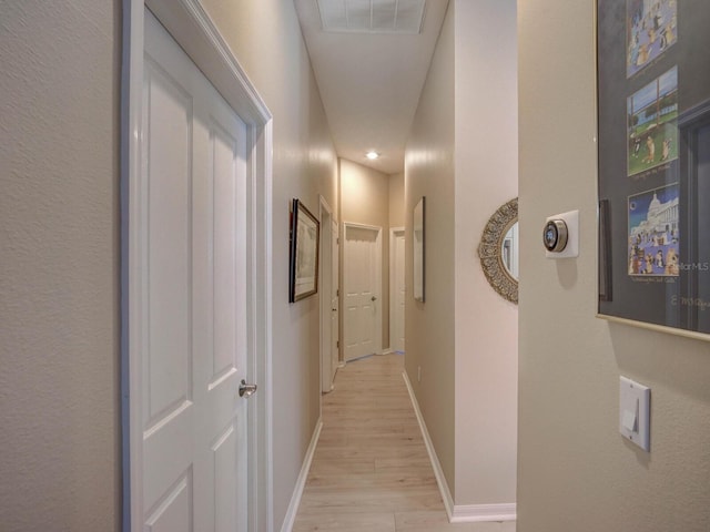 hall featuring light wood-style floors, visible vents, and baseboards