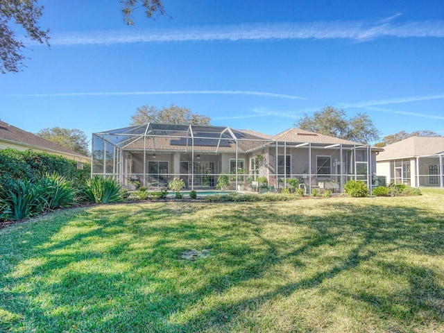 back of house with a lanai and a lawn