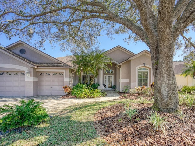 single story home with french doors, driveway, an attached garage, and stucco siding