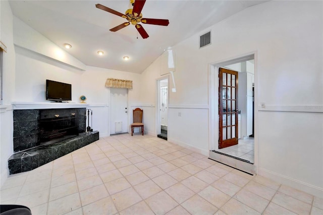 unfurnished living room featuring lofted ceiling, visible vents, a tiled fireplace, ceiling fan, and tile patterned flooring