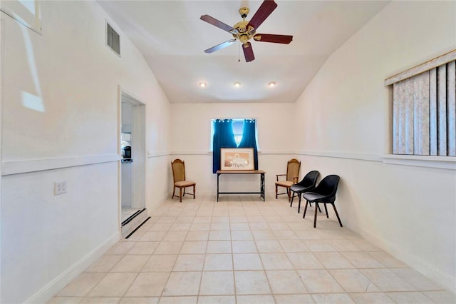 living area featuring light tile patterned floors, visible vents, ceiling fan, vaulted ceiling, and baseboards