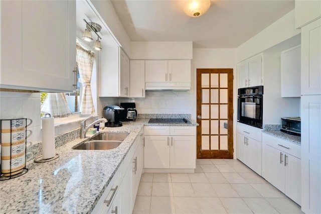 kitchen featuring tasteful backsplash, under cabinet range hood, black appliances, white cabinetry, and a sink