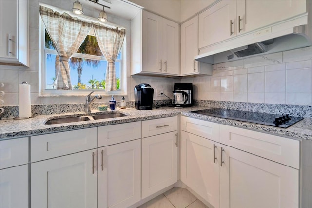 kitchen with black electric stovetop, a sink, white cabinets, and under cabinet range hood