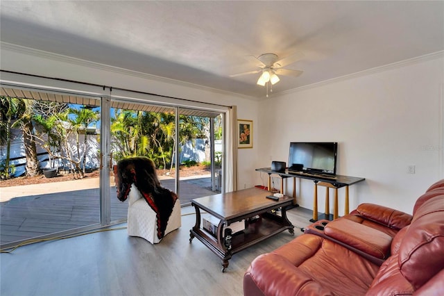 living area with ceiling fan, ornamental molding, and wood finished floors