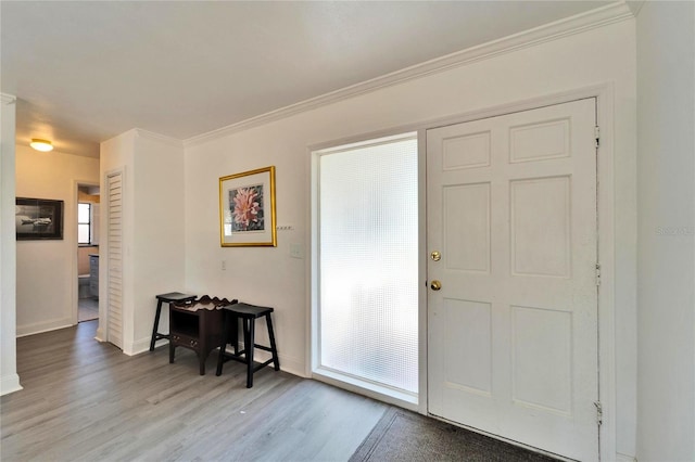 foyer featuring crown molding, baseboards, and wood finished floors