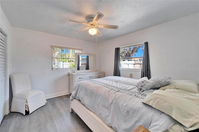 bedroom with multiple windows, ceiling fan, baseboards, and wood finished floors