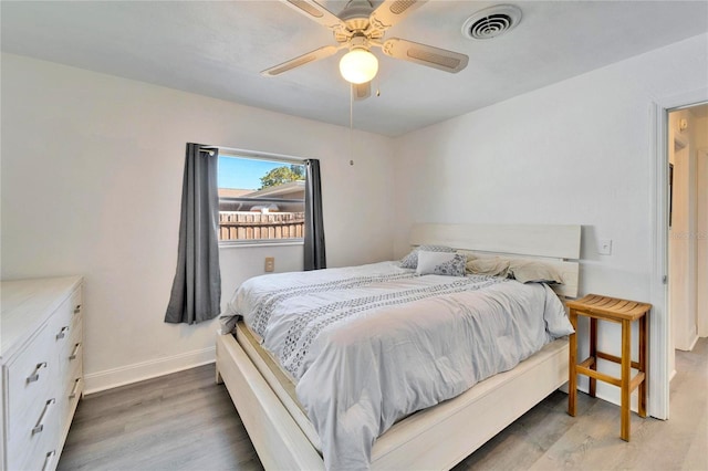 bedroom with baseboards, visible vents, ceiling fan, and wood finished floors