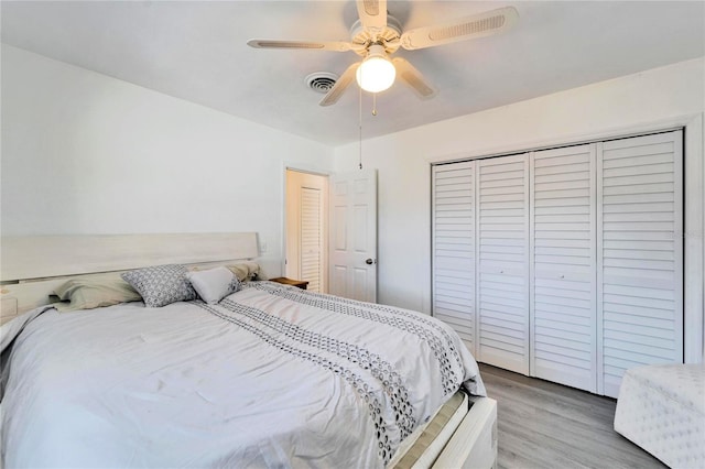 bedroom featuring ceiling fan, a closet, wood finished floors, and visible vents