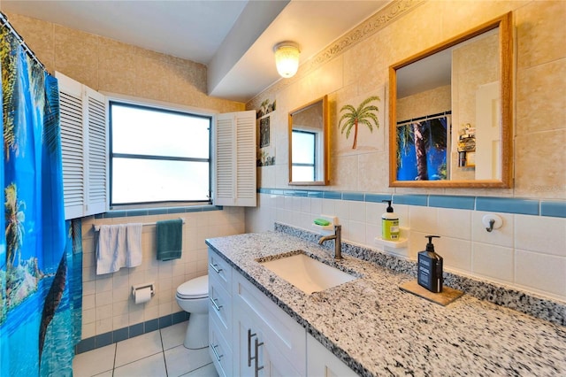 bathroom with tile walls, a shower with shower curtain, toilet, vanity, and tile patterned floors