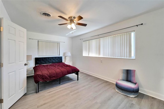 bedroom featuring baseboards, visible vents, ceiling fan, and wood finished floors