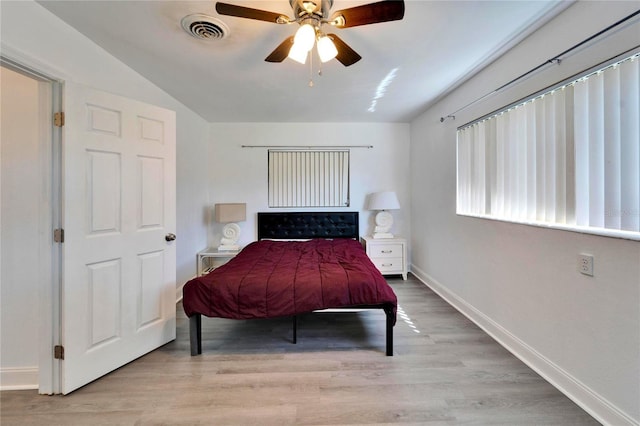 bedroom with a ceiling fan, wood finished floors, visible vents, and baseboards